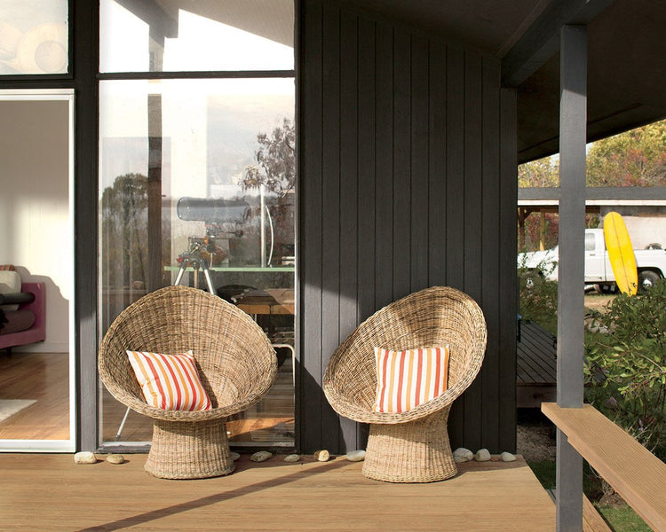 two whicker chairs with red striped white pillows on wooden deck