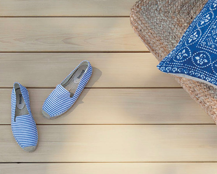 Top down view of striped blue shoes and chair with blue pillow on wooden deck